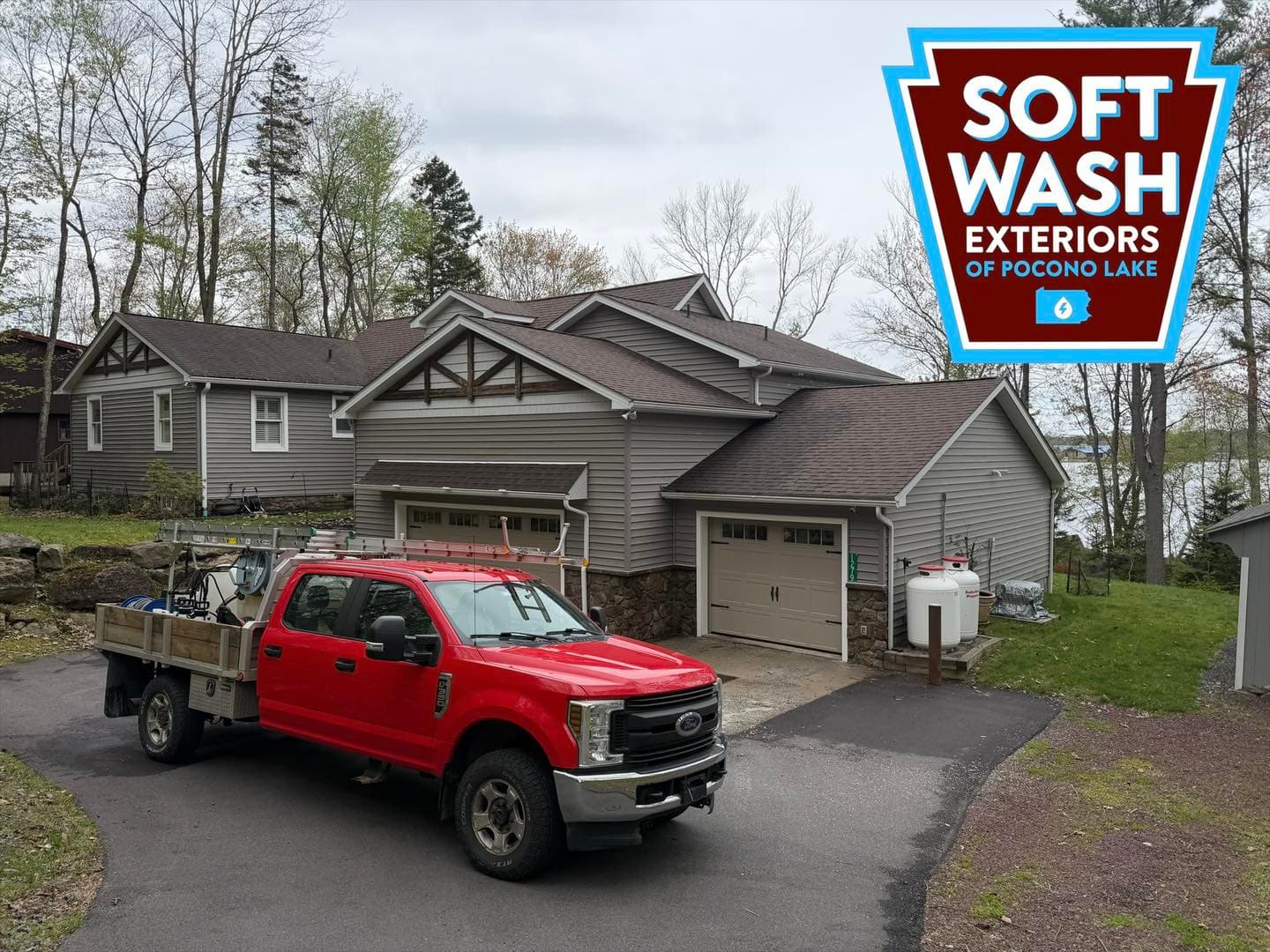 Gray lakehouse, red truck, lake in background